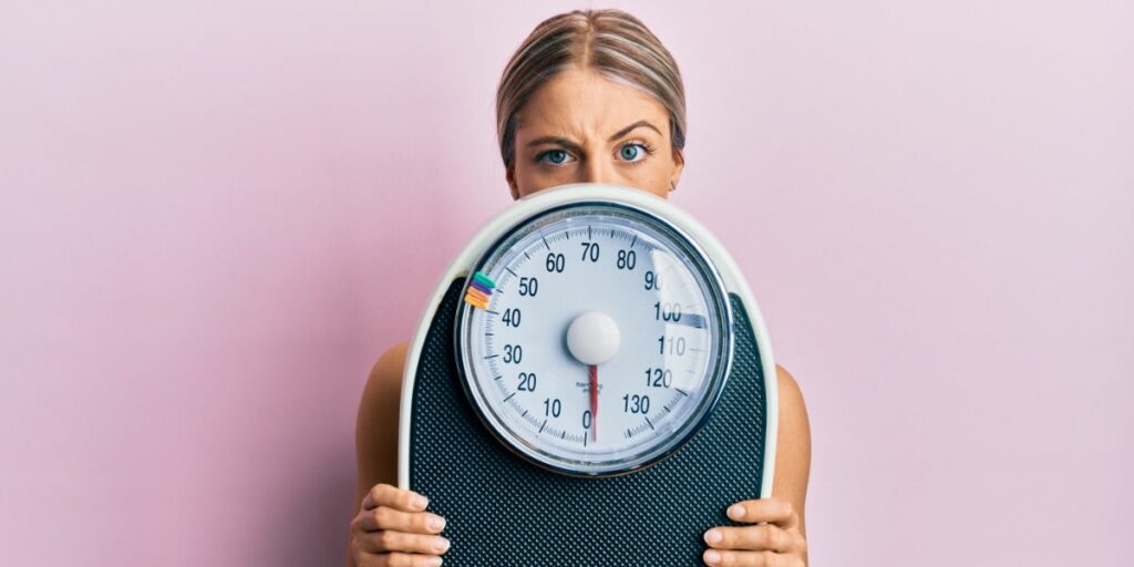 Une femme tient une balance avec un air confus